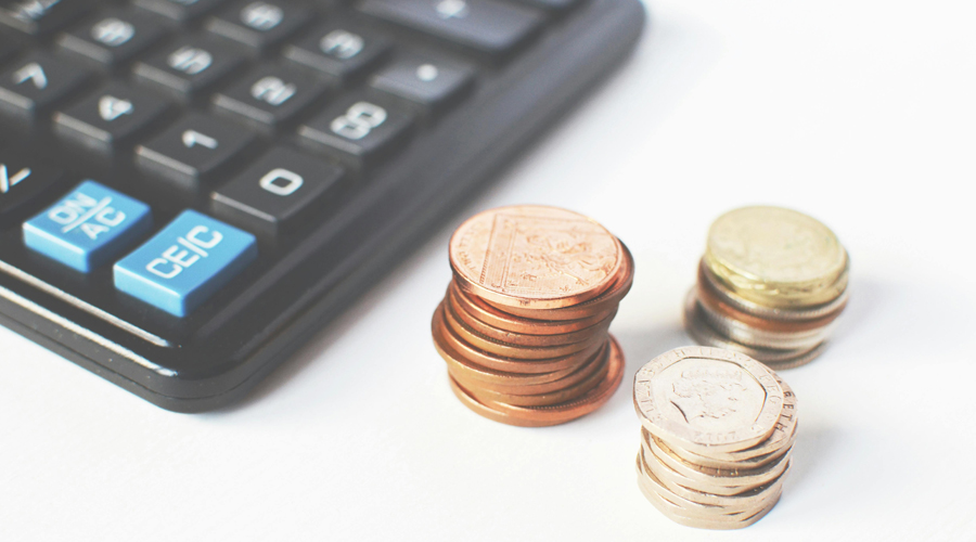 Foto di una calcolatrice nera e alcune monete su sfondo bianco