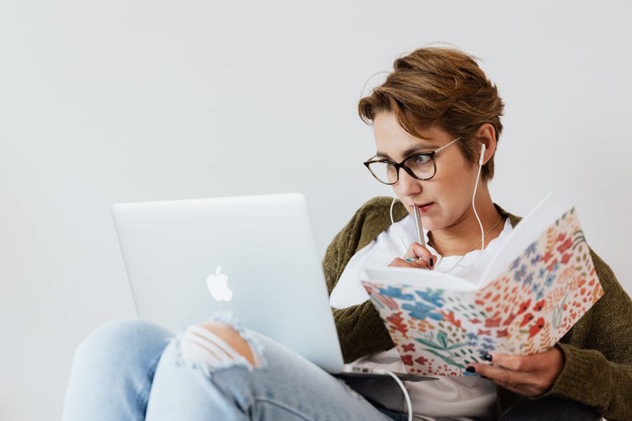 Donna che legge lo schermo di un computer con in mano un libro