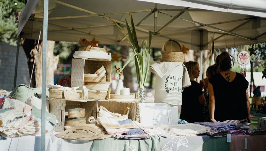 mercatino che vende prodotti di sartoria, con persone in secondo piano, 