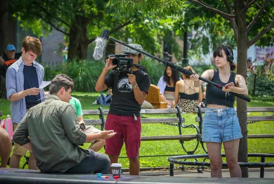 Ragazzi e ragazze dietro a un set cinematografico con riprese, copioni e scene di un film