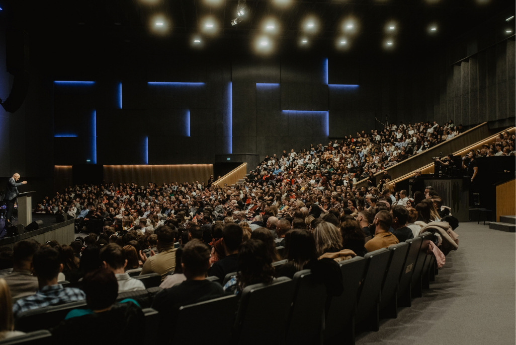 Un ampio pubblico ascolta attentamente un relatore a una conferenza 