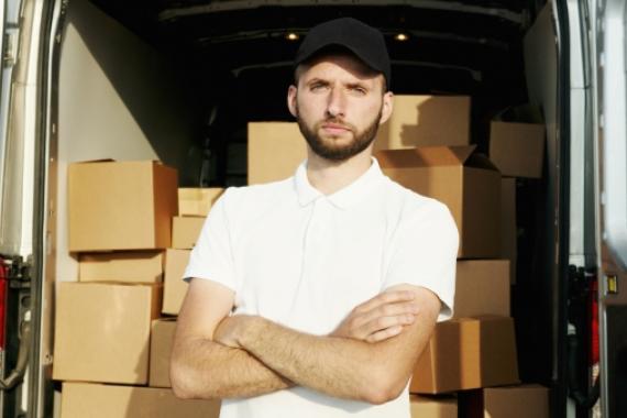 Ragazzo con pacchi di consegna nello sfondo; organizzazione, logistica, trasporti.