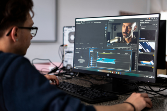 Un video editor lavora a un progetto utilizzando un computer desktop in un moderno ufficio