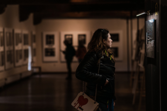 donna che guarda un'opera artistica in un museo scarsamente illuminato